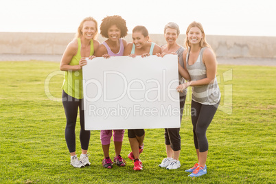 Smiling sporty women holding poster with copy space
