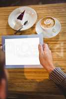 Man with tablet having cappuccino and cake