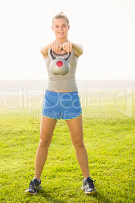 Smiling sporty blonde exercising with kettlebell