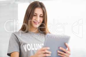 Smiling brunette volunteer using tablet