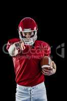 Portrait of american football player holding football and pointi