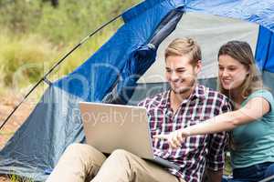 Young pretty hiker couple sitting in a tent looking at laptop