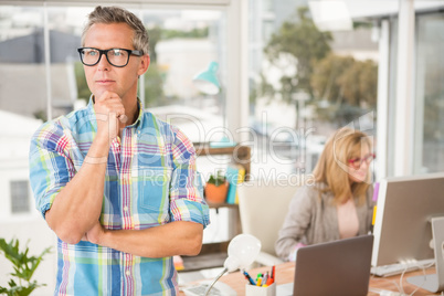 Thoughtful casual designer in front of his working colleague