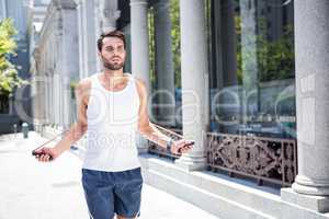 Handsome athlete skipping with jump rope