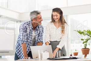 Smiling business colleagues using laptop