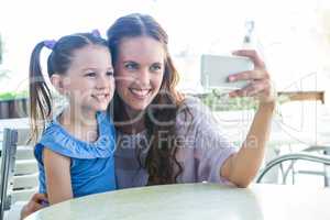 Mother and daughter taking selfie at cafe terrace