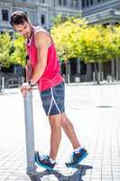 Handsome athlete doing leg stretching on a stake