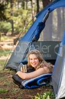 Pretty blonde camper smiling and lying in tent