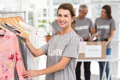 Smiling female volunteer choosing clothes