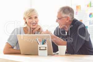 Smiling business team working on laptop