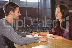 Smiling couple holding hands and having coffee together