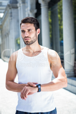 Concentrated handsome athlete checking heart rate watch