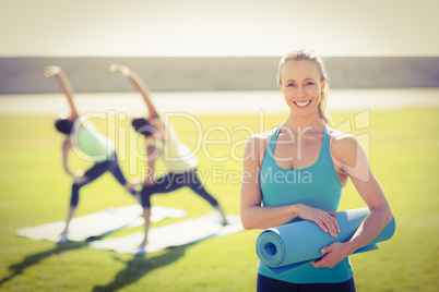 Smiling sporty blonde in front of friends doing exercises