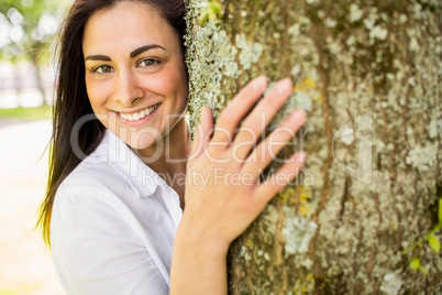 Beautiful brunette hugging a tree