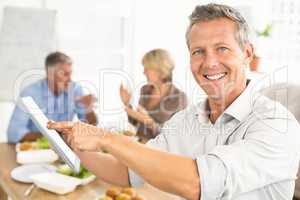 Smiling casual businessman using tablet at lunch