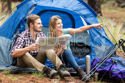 Young pretty hiker couple sitting in a tent pointing