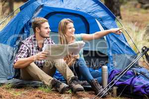 Young pretty hiker couple sitting in a tent pointing