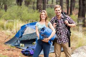 Portrait of a young pretty hiker couple holding a sleeping bag a