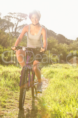 Smiling athletic brunette mountain biking