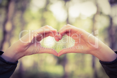 Carefree female hiker framing heart with hands