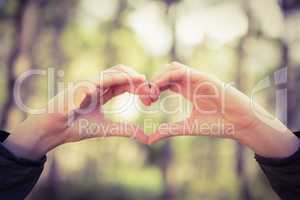 Carefree female hiker framing heart with hands