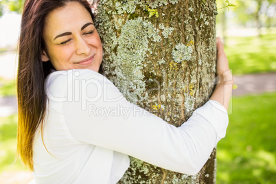 Beautiful brunette hugging a tree