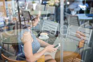 Pretty woman using her phone having a coffee