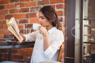 Beautiful businesswoman having a coffee reading book