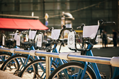 standing in a number of bicycles for hire on a city street