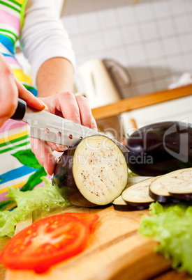 Woman's hands cutting aubergine eggplant