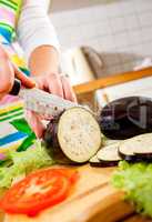 Woman's hands cutting aubergine eggplant