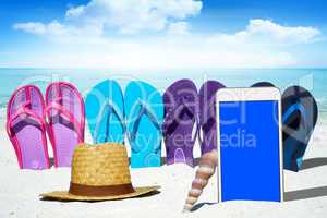 Smartphone mit leerem Display und bunte Flip Flops am Strand