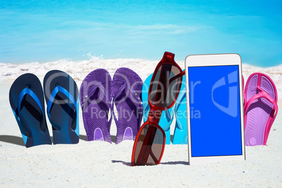 Smartphone mit leerem Display und bunte Flip Flops am Strand