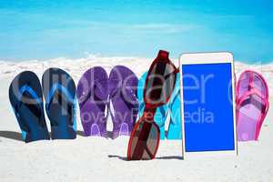 Smartphone mit leerem Display und bunte Flip Flops am Strand
