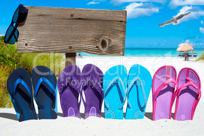 Flip flops und ein Holzschild mit Textfreiraum am Sommerstrand