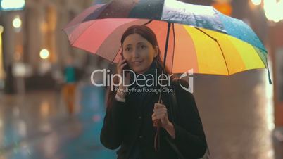 Brunette woman talks on the phone on the street on rainy day