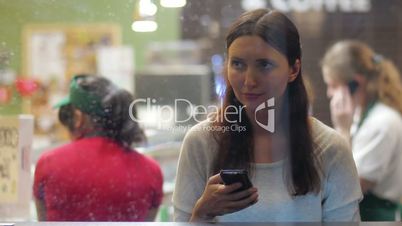 Young brunette girl using smartphone in the cafe