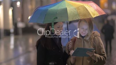 Women talking on the street on rainy day