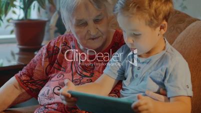 Grandmother and grandson use tablet at home
