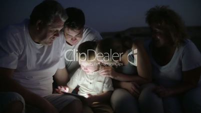 Big family and child with pad outdoor at night