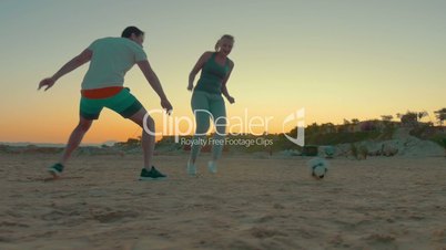 People having fun during football playing on the beach