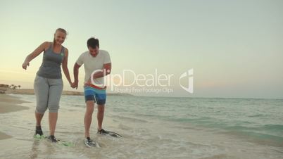 Couple in flippers walking clumsy along the shore