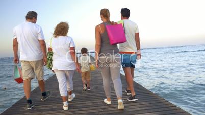 Big family with shopping bags on pier in the sea