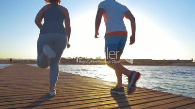 Young people jogging on the pier at sunset