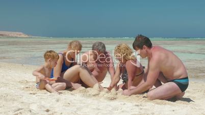 Big family building sand castle together