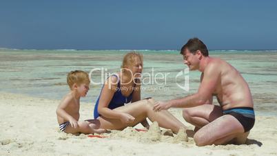 Parents and son playing with sand on the beach