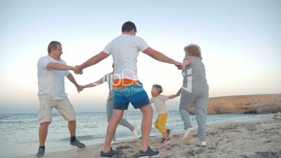 Family circle dancing on the coast