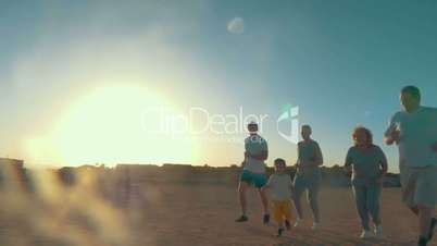 Family run on the beach at sunset