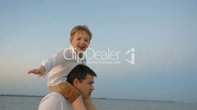 Child showing plane sitting on fathers shoulders