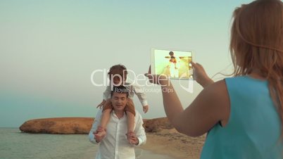 Mother with pad shooting father and son on beach